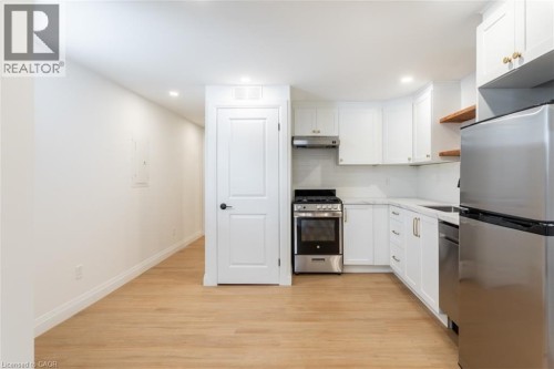 Kitchen with stainless steel appliances, white cabinetry, light wood-type flooring, recessed lighting, and open shelves