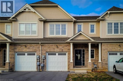 Townhome facade featuring brick and siding construction, a covered porch with white columns, and multiple windows