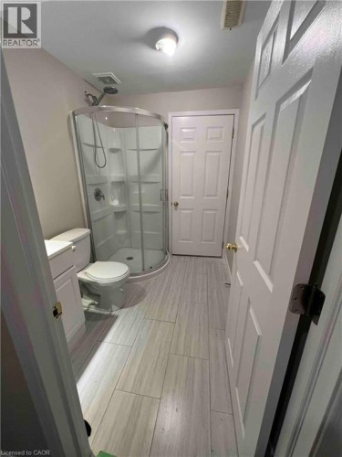 Bathroom featuring a corner shower enclosure with clear glass, a white toilet, and a white vanity with a cabinet
