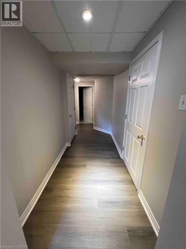 Hallway featuring wood-finish flooring, light gray walls, and white trim