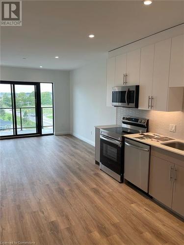 Kitchen featuring backsplash, white cabinetry, stainless steel appliances, and light hardwood / wood-style flooring