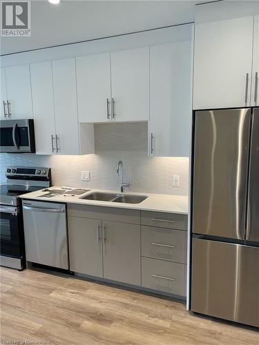 Kitchen with white cabinetry, sink, decorative backsplash, appliances with stainless steel finishes, and light wood-type flooring