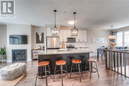 Kitchen with appliances with stainless steel finishes, dark hardwood / wood-style flooring, sink, a center island with sink, and white cabinets