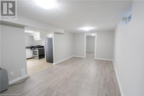 Basement with light hardwood / wood-style flooring and stainless steel fridge