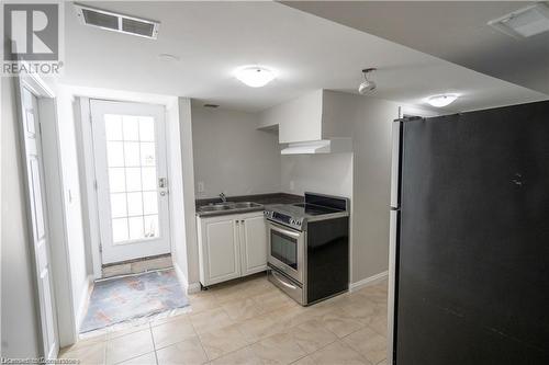 Kitchen with extractor fan, white cabinetry, sink, stainless steel appliances, and light tile patterned flooring